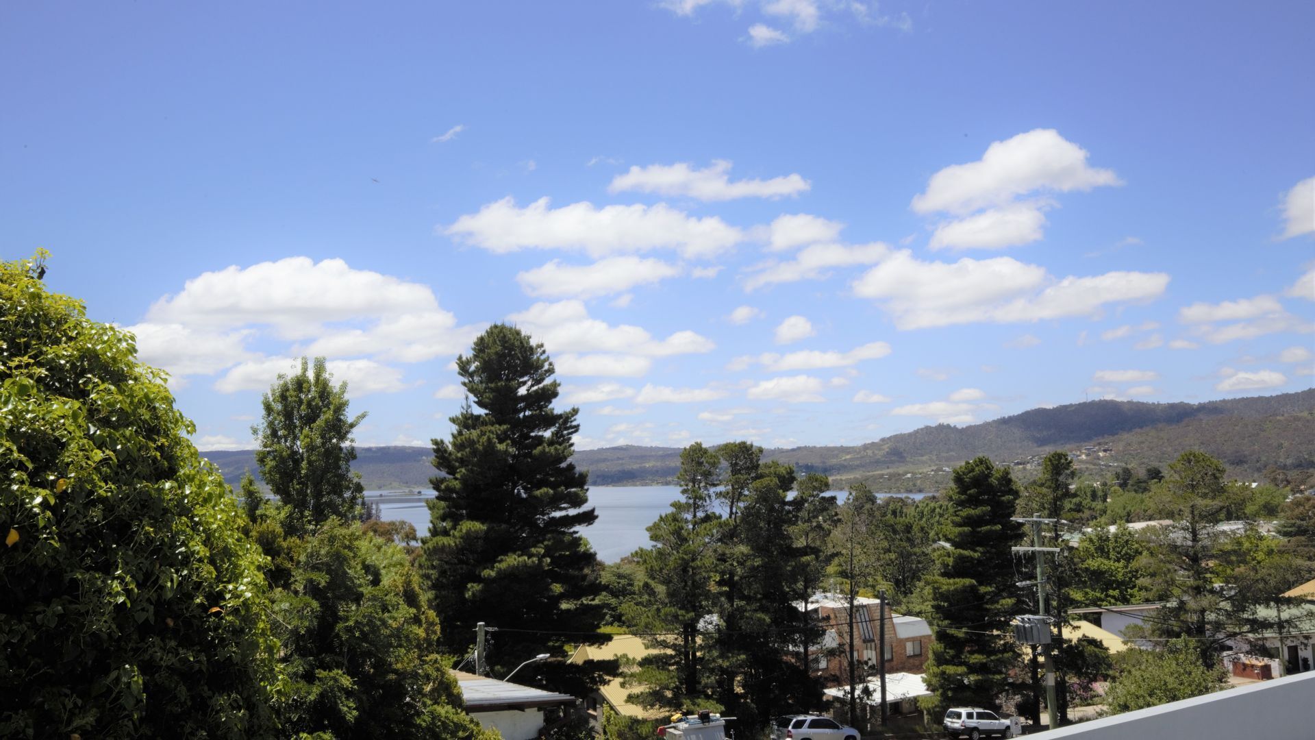 A residential area with houses, trees, and a lake in the background.