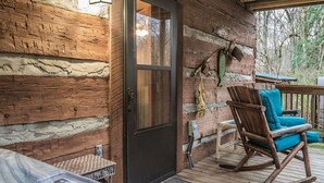 Une cabane en bois avec un bain à remous, une chaise berçante et une porte.