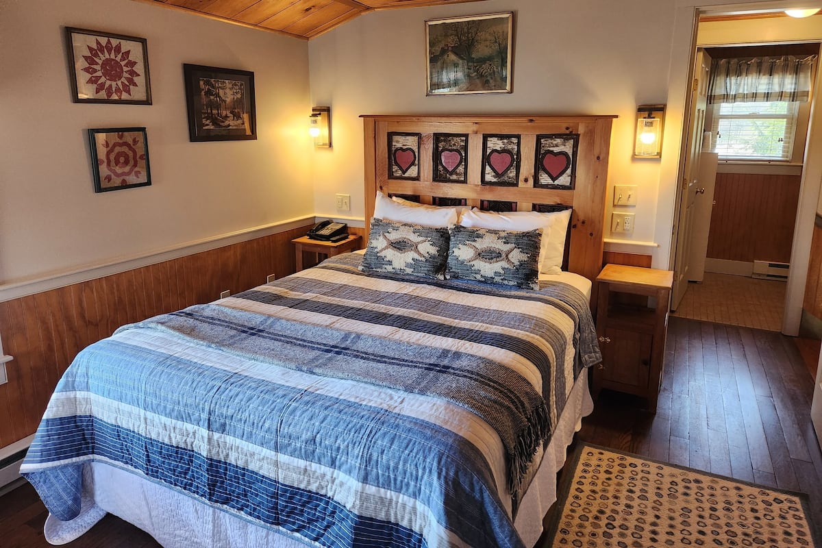 A bedroom with a wooden headboard, a striped bedspread, and multiple wall-mounted lights.