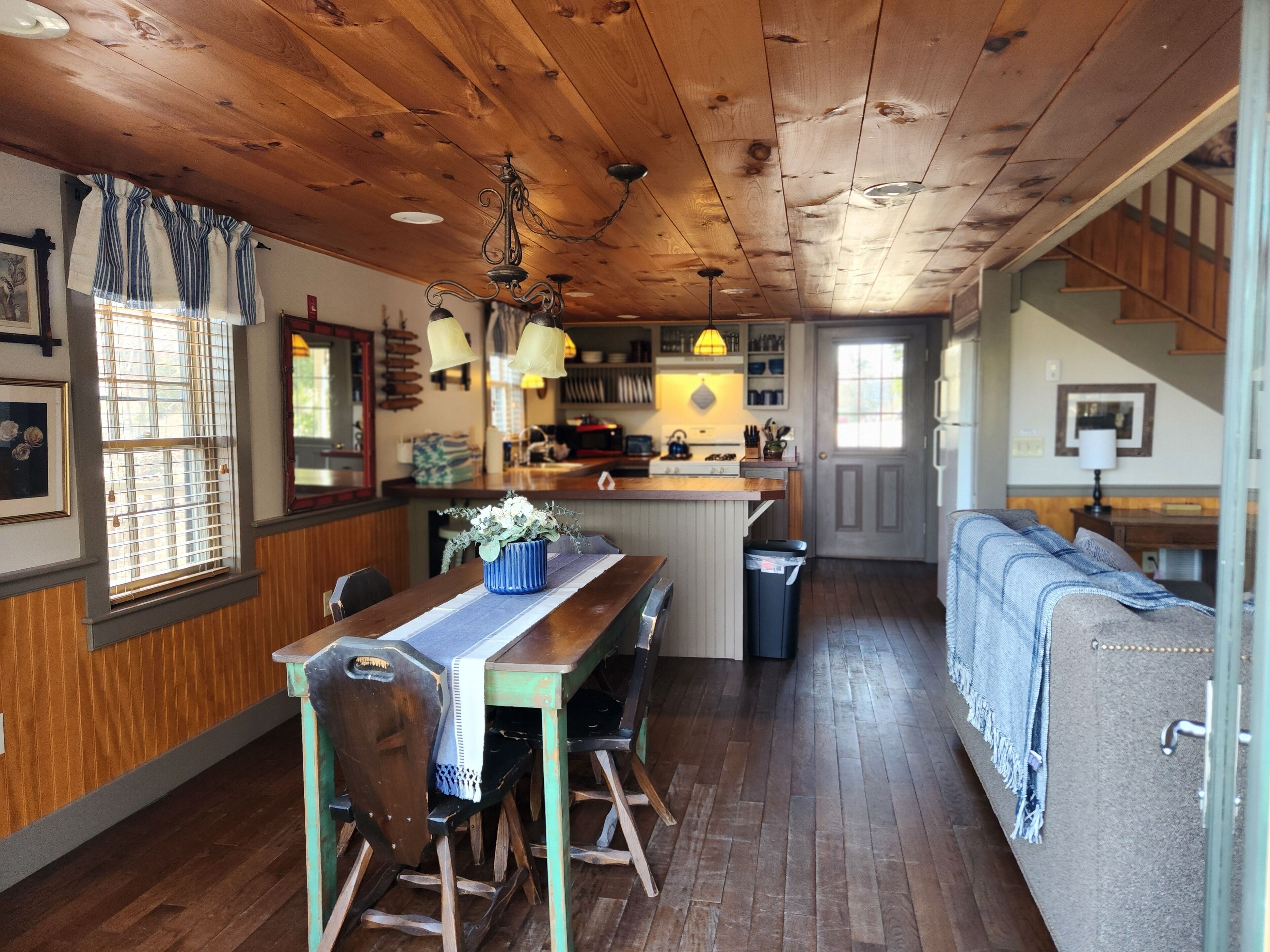 A cozy kitchen with wooden cabinets, a dining table with chairs, and a built-in island with a sink.