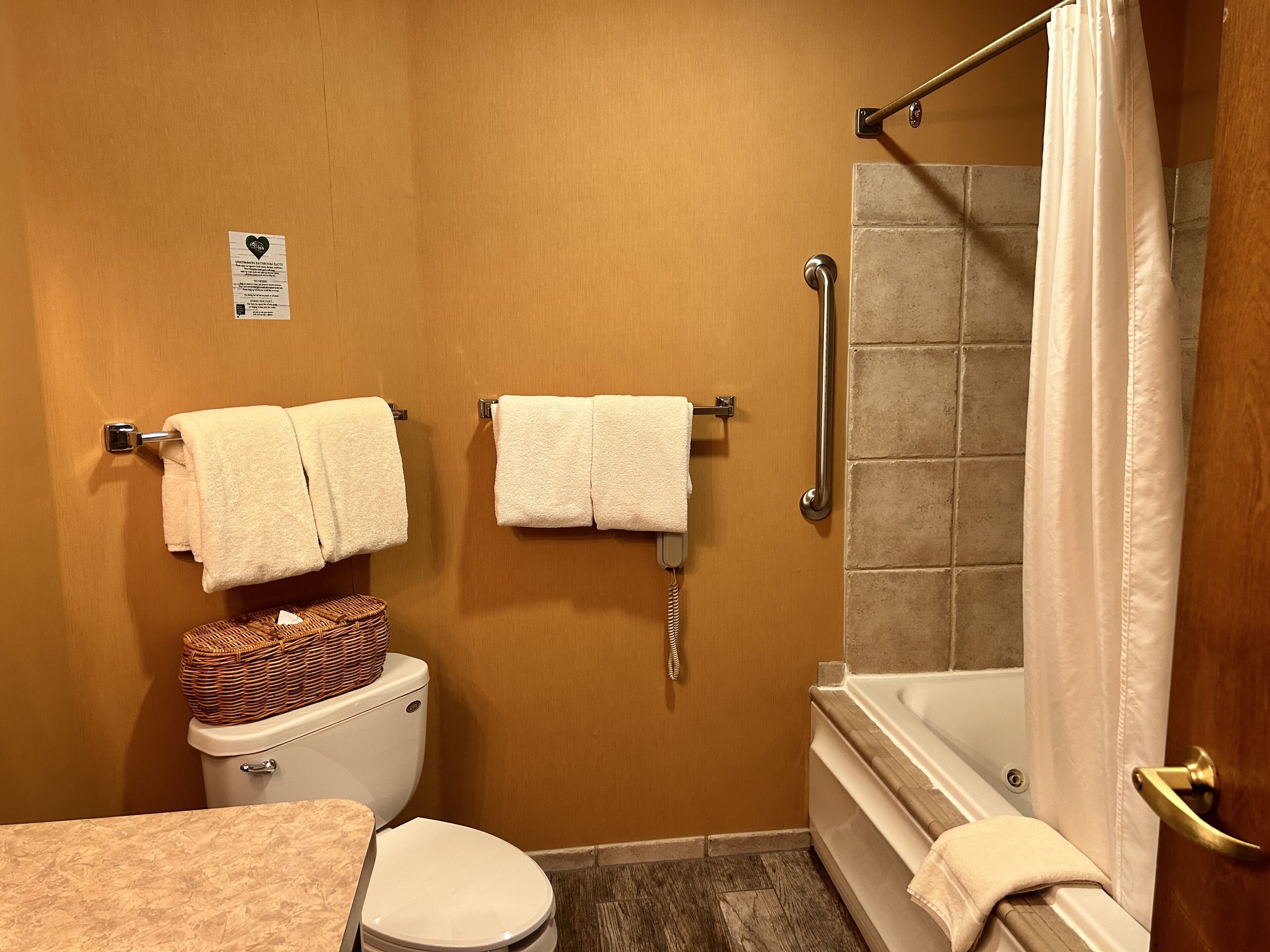 A bathroom with a toilet, a shower, and two towels hanging on towel bars.