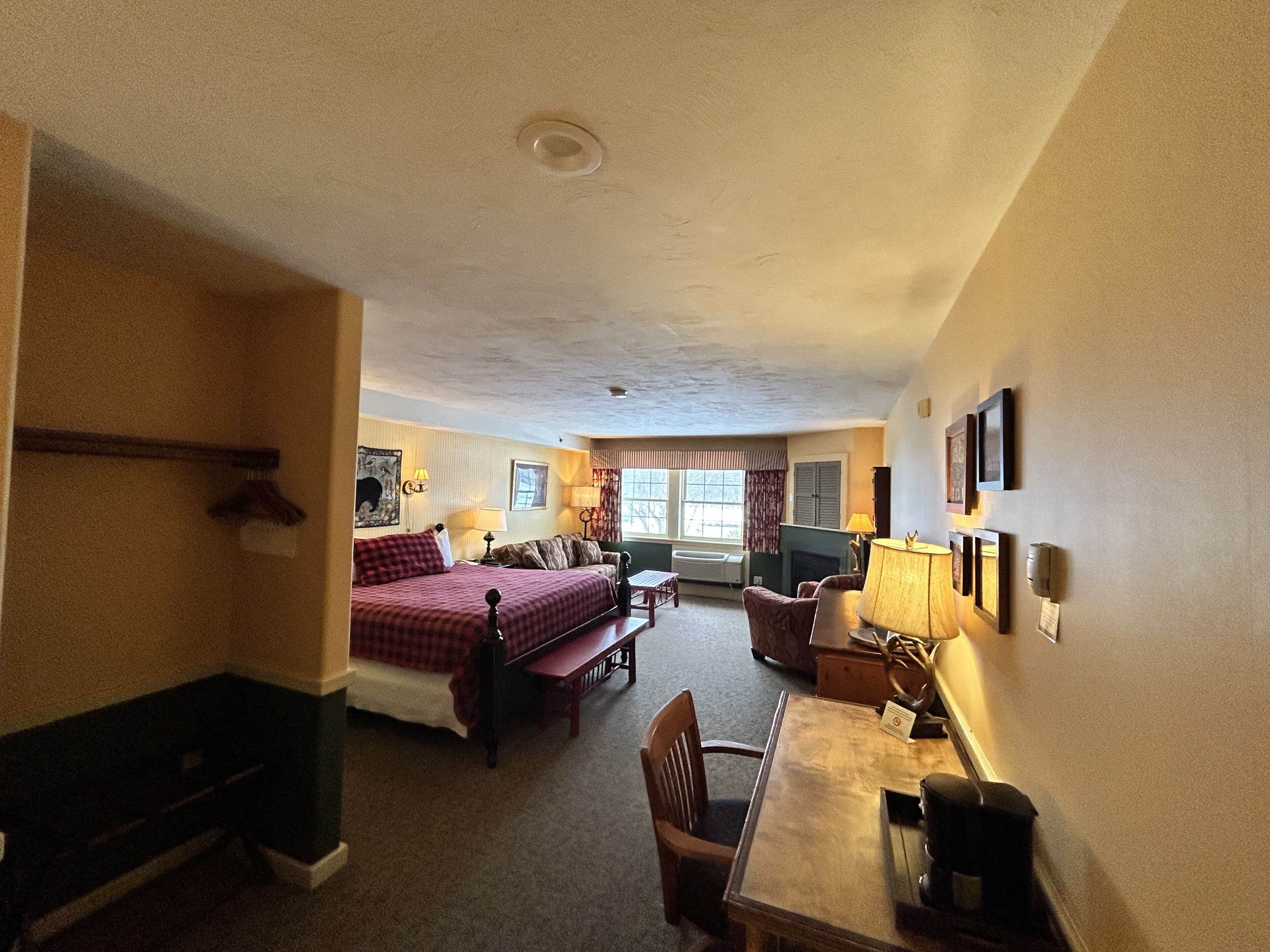 Una habitación de hotel con cama, escritorio, silla, chimenea y ventana.
