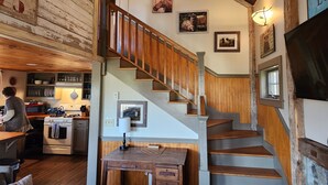 Un intérieur rustique avec un escalier en bois, un coin cuisine et un espace repas.