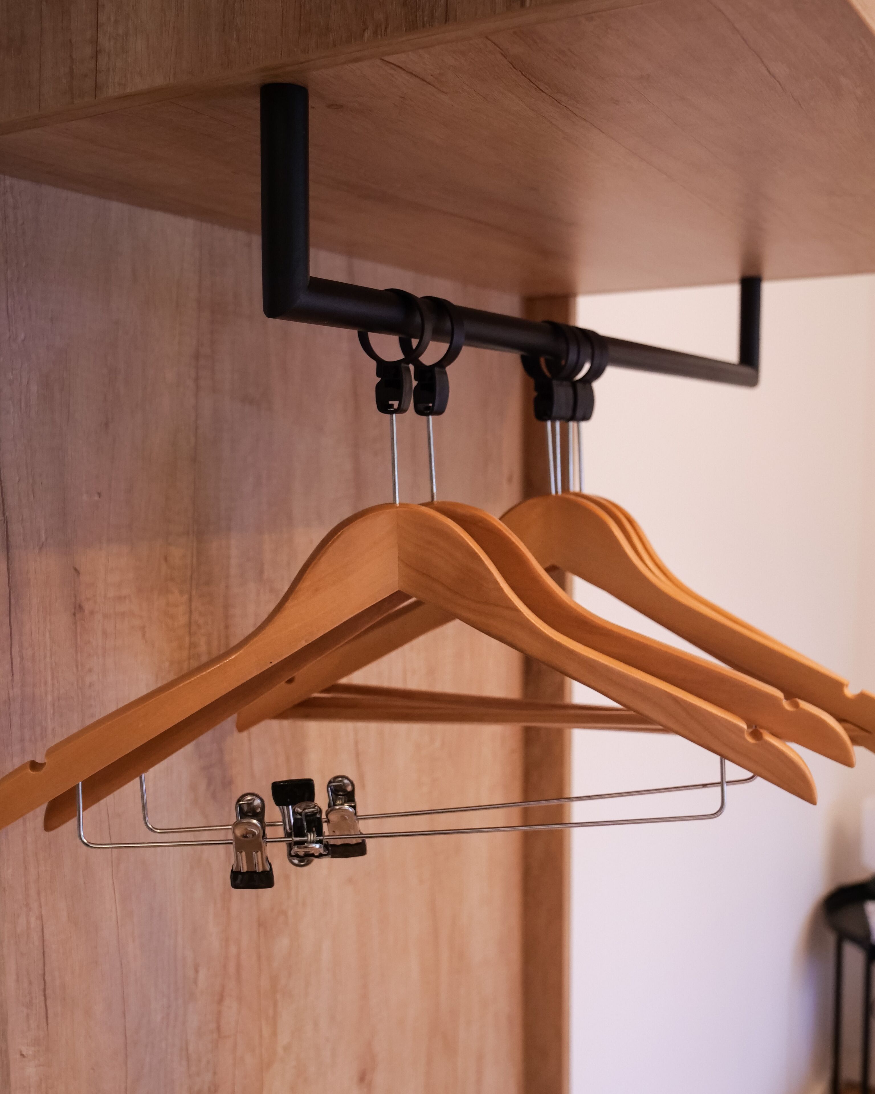 A wooden hanger rack with two wooden hangers and a metal wire rack.