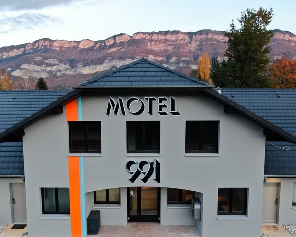 Un motel con diseño moderno, que destaca un llamativo letrero con la palabra 'MOTEL' y el número '991' en su fachada.