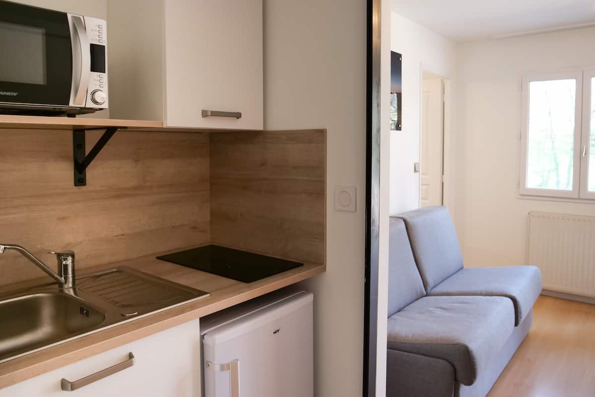 Eine kleine Küchenzeile mit Mikrowelle, Spüle und kleinem Kühlschrank.