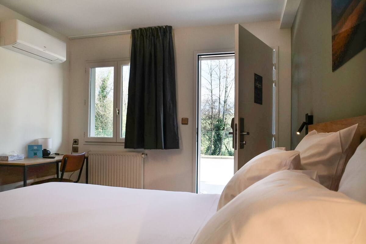 Ein Hotelzimmer mit Bett, Schreibtisch, Stuhl, Heizkörper und einem fensterbepflegten Fenster.