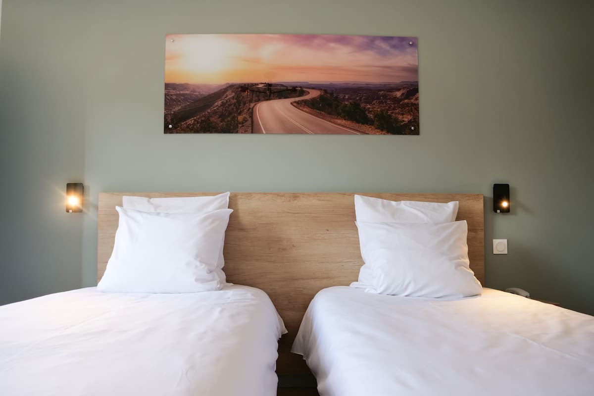 Ein Doppelbett mit weißen Leinen, ein Holzkopfseitenverkleidung und zwei an der Wand befestigte Leuchten.