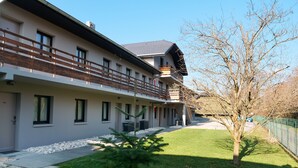 A modern two-story building with a balcony, a small tree, and a well-maintained lawn. - Motel 991 (Viviers-du-Lac)