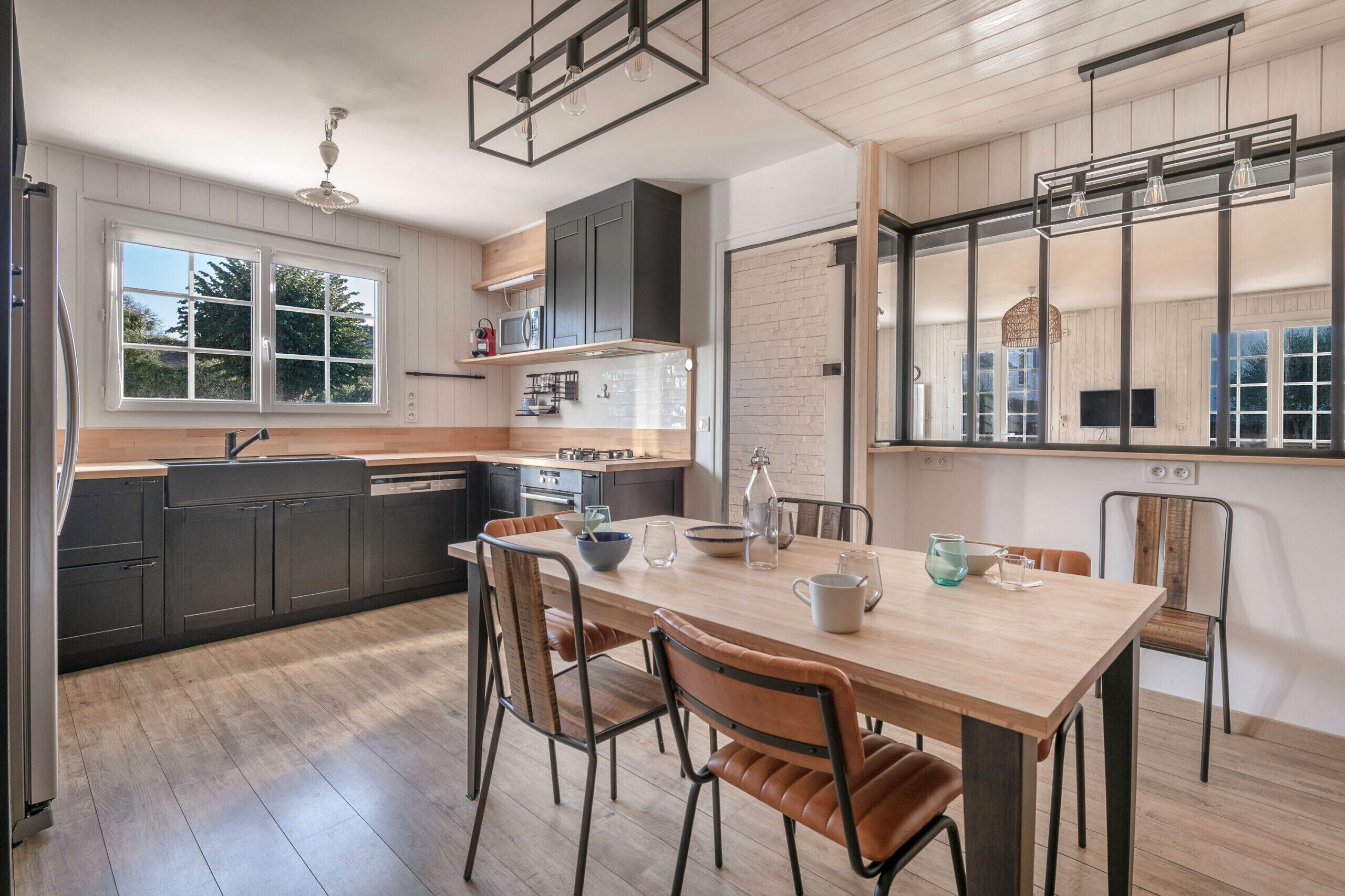 A modern kitchen with wooden cabinets, a central island, and a dining area with chairs.