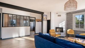 A modern living room with a blue sofa, yellow chairs, a wooden coffee table, and a hanging light fixture. - Arzon - Large family house, garden - 11 guests (Arzon)