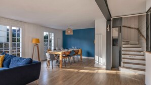 A spacious living area with a dining table, a sofa, and a staircase. - Arzon - Large family house, garden - 11 guests (Arzon)