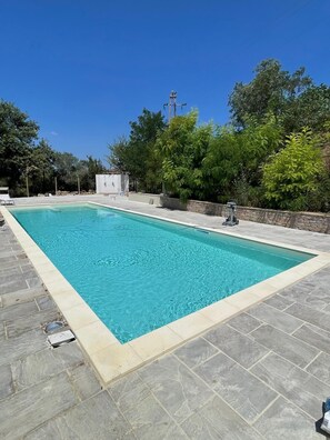 Una piscina al aire libre, sombrillas, tumbonas