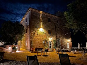 A stone building with a courtyard, outdoor seating, and string lights. - LOCANDA DELLA PICCA (Citta della Pieve)