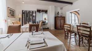 Un comedor con una mesa preparada para cuatro, una vinoteca y vistas a la cocina.