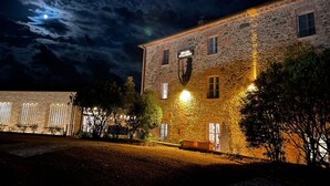 Un edificio de piedra con un letrero que dice "Hotel del Rey", iluminado con luces exteriores durante la noche.