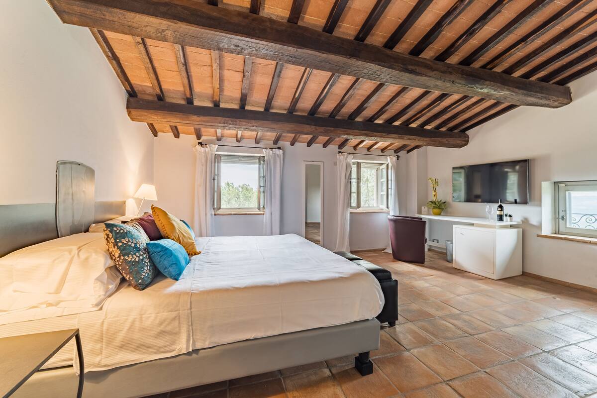 Ein Schlafzimmer mit Bett, Schreibtisch, Fernseher und Fenster.
