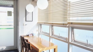 A restaurant interior with a wooden table and chairs, large windows with blinds, and hanging spherical light fixtures. - Hostel Kpop (Seoul)