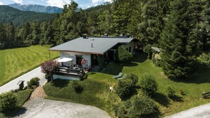A house with a covered patio, surrounded by a well-maintained lawn and dense forest. - bright apartment with a large sun terrace and access to the garden (Reith bei Seefeld)