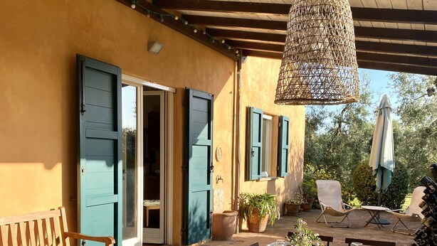 An outdoor dining area with a wooden table set for a meal, surrounded by chairs, and a hanging wicker light fixture. - Tuscan countryhouse apartment, 10 min by the sea,  with AC and large garden. (Castagneto Carducci)