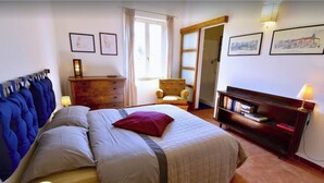 A bedroom with a bed, a dresser, a chair, a bookshelf, and a door leading to another room. - Tuscan countryhouse apartment, 10 min by the sea,  with AC and large garden. (Castagneto Carducci)