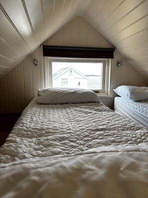 A bedroom with a bed, a window, and a view of a building across the water.
