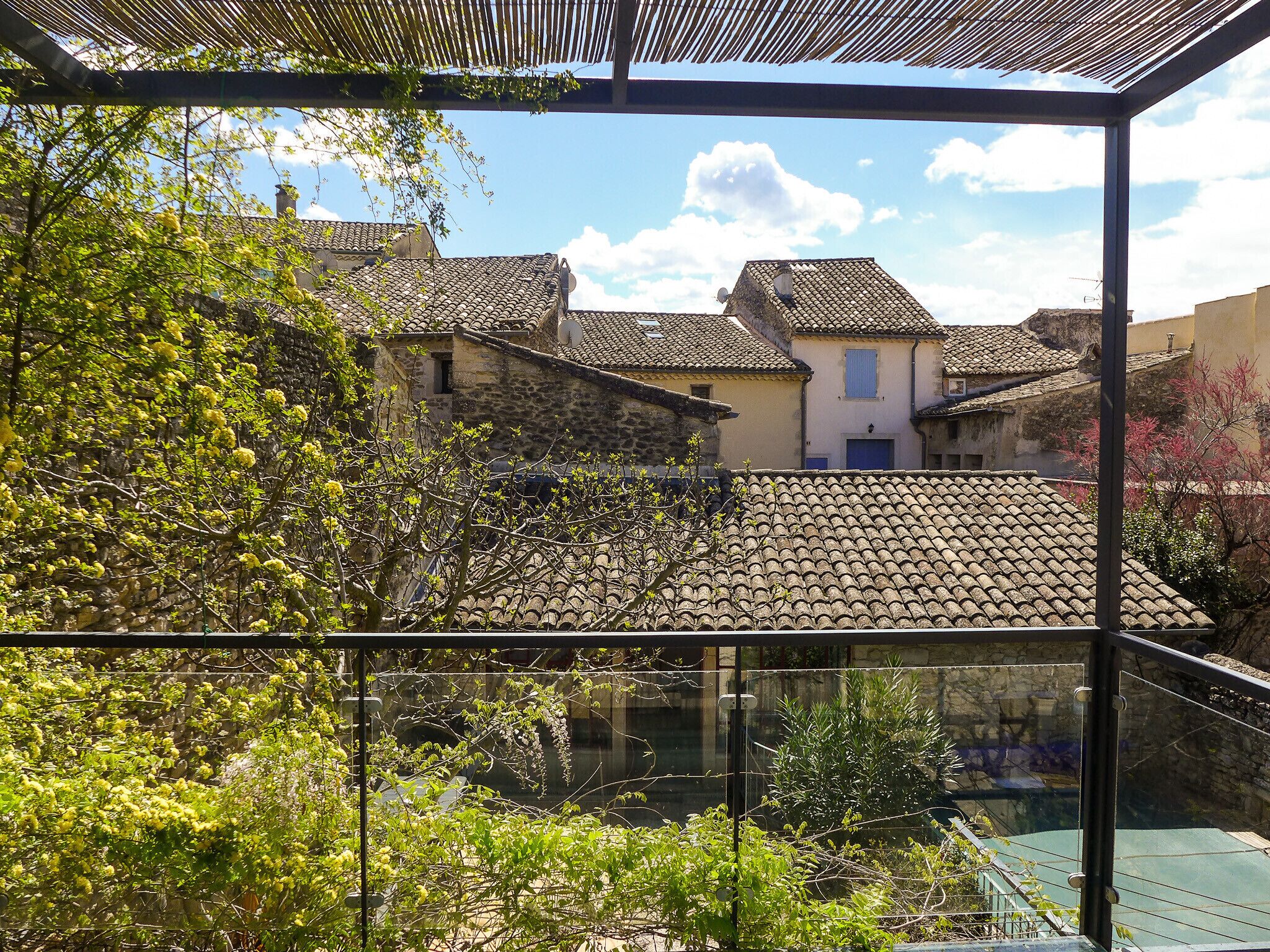 Vista des d'un balcó amb barana de vidre, que donava al jardí interior ple d'edificis tradicionals i vegetació.