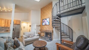A modern living room with a fireplace, a staircase, and a kitchen in the background. - Flying Dutchman 1106 (Keystone)