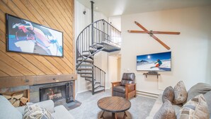 A living room with a fireplace, a round coffee table, a sofa, and a television mounted on the wall. - Flying Dutchman 1106 (Keystone)