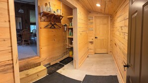 A wooden interior with a door, a shelf with bottles, and a chair. - Cozy Cabin located directly on the ORV trail. Peace & seclusion. (Hulbert)