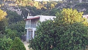 A residential area with a modern two-story house, a paved driveway, and a red car parked on the street. - Beautiful 3-bed House in Chania With Garden (Platanias)