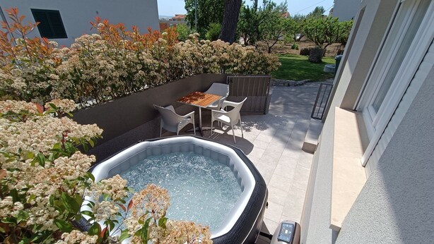 A hot tub with a control panel, surrounded by a patio area with chairs and a table. - Holiday Home Relax (Podstrana)
