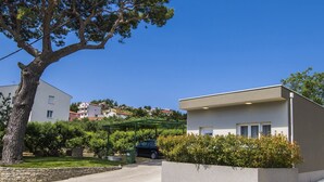 A modern building with a stone wall and a tree in front. - Holiday Home Relax (Podstrana)