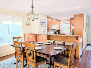 A kitchen with wooden cabinets, a dining table with chairs, and a hanging light fixture.