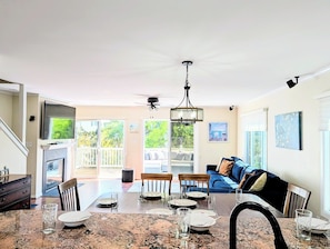 A spacious living room with a dining area, a blue sofa, and a ceiling fan.