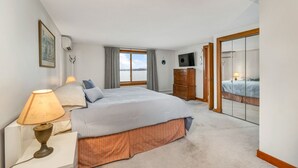 A bedroom with a bed, a dresser, a television, and a window with curtains. - Waterfront home sleeping 10 located on Cummings Cove on Lake Winnipesaukee (Meredith)