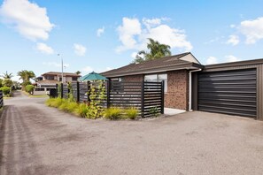 A residential street with houses, a gated driveway, and a garage door.