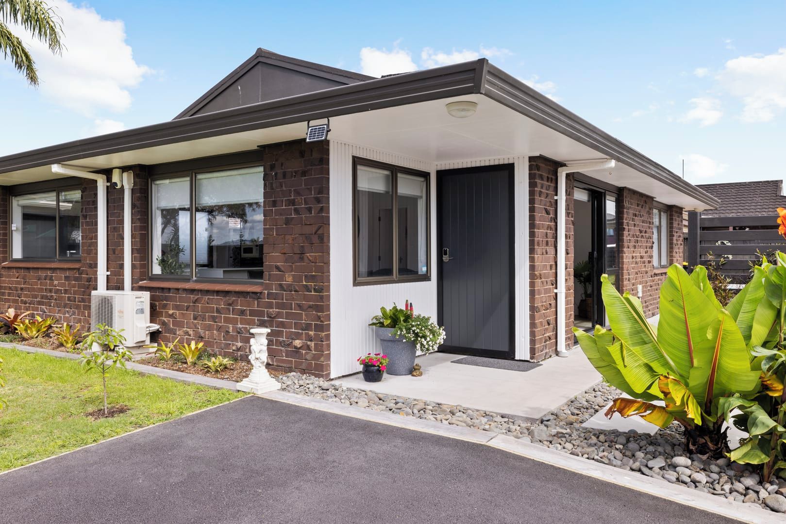 Une maison moderne à deux étages, dotée d’une façade en briques, de grandes fenêtres et d’un porche abrité.