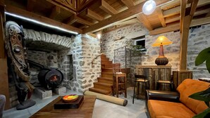 A rustic interior with a stone fireplace, wooden beams, a sofa, and a dining table. - Superb 450 m2 farmhouse fully restored in Haute Loire (Araules)
