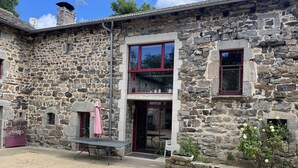 A stone building with a large window, a door, and a small balcony. - Superb 450 m2 farmhouse fully restored in Haute Loire (Araules)