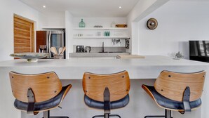 A modern kitchen with a central island, wooden chairs, and a built-in oven. - Luxury villa overlooking the Laguna Marina (Kralendijk)