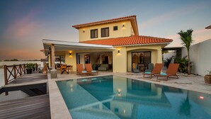 A modern house with a swimming pool, outdoor seating, and a patio area. - Luxury villa overlooking the Laguna Marina (Kralendijk)