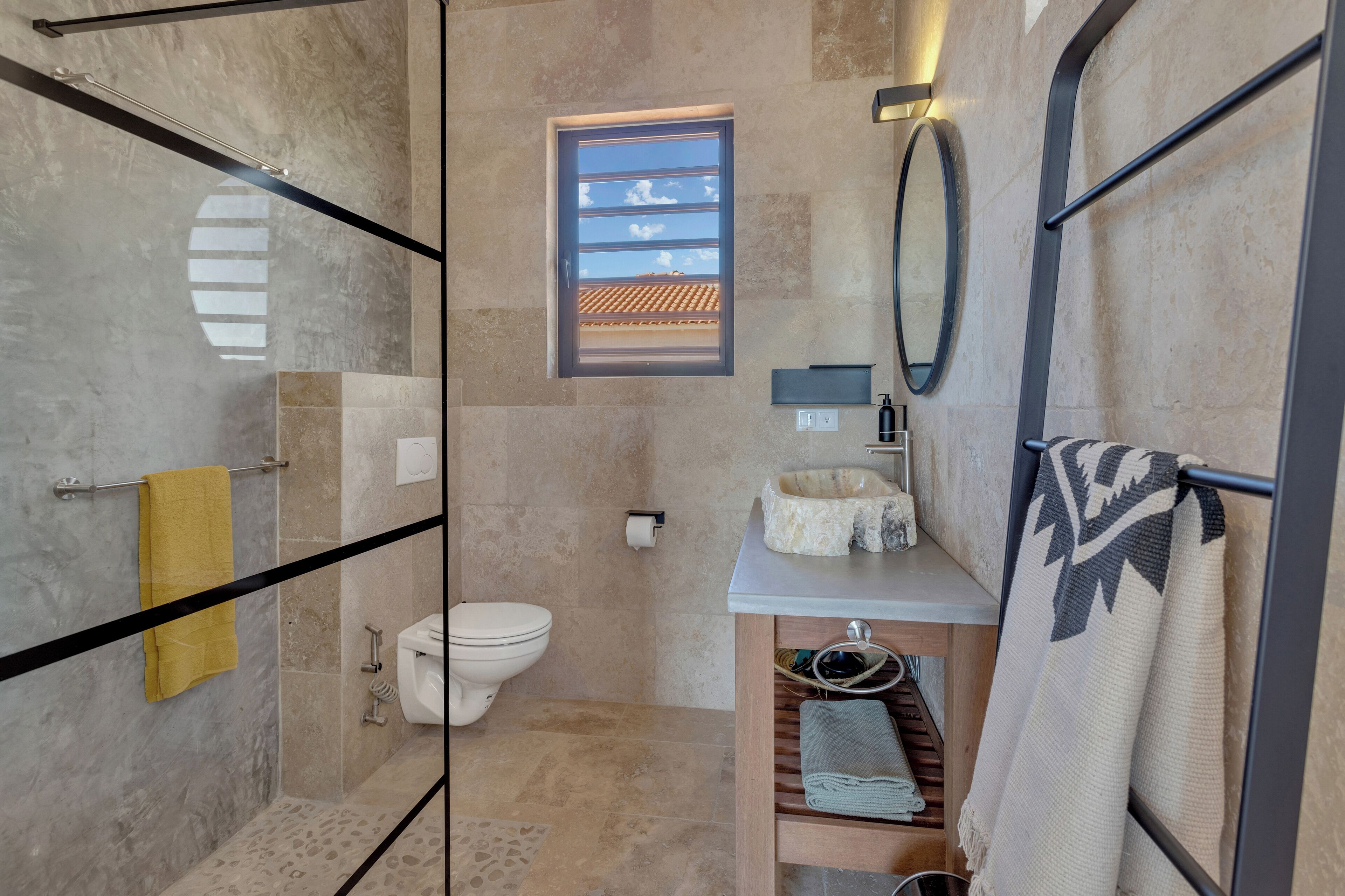 A modern bathroom with a glass shower enclosure, a toilet, a sink with a mirror, and a towel rack.