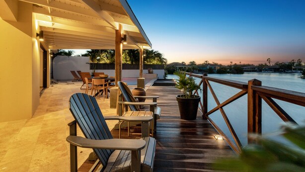 A wooden deck with outdoor seating and a view of the water. - Luxury villa overlooking the Laguna Marina (Kralendijk)