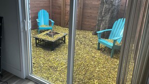 A patio area with two blue Adirondack chairs, a fire pit, and a wooden fence. - Casa Wooten -Contemporary Condo (Austin)