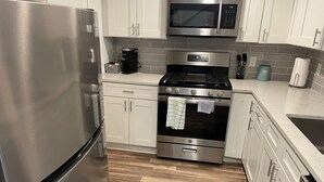 A modern kitchen with stainless steel appliances, white cabinetry, and a wood floor. - Casa Wooten -Contemporary Condo (Austin)