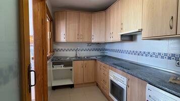 Una cocina con armarios de madera, horno empotrado, lavavajillas y lavadora.