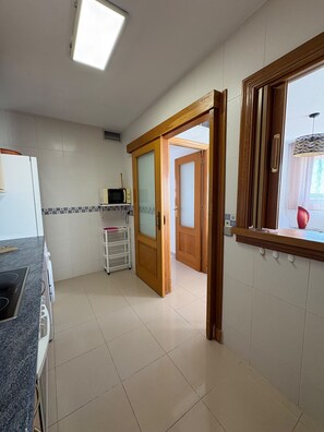 Een keuken met een magnetron, een wit schap en een houten deur naar een andere kamer.
