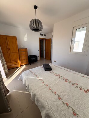 Ein Schlafzimmer mit einem großen Bett, einem Kleiderschrank, einem Schreibtisch und einem Fenster.