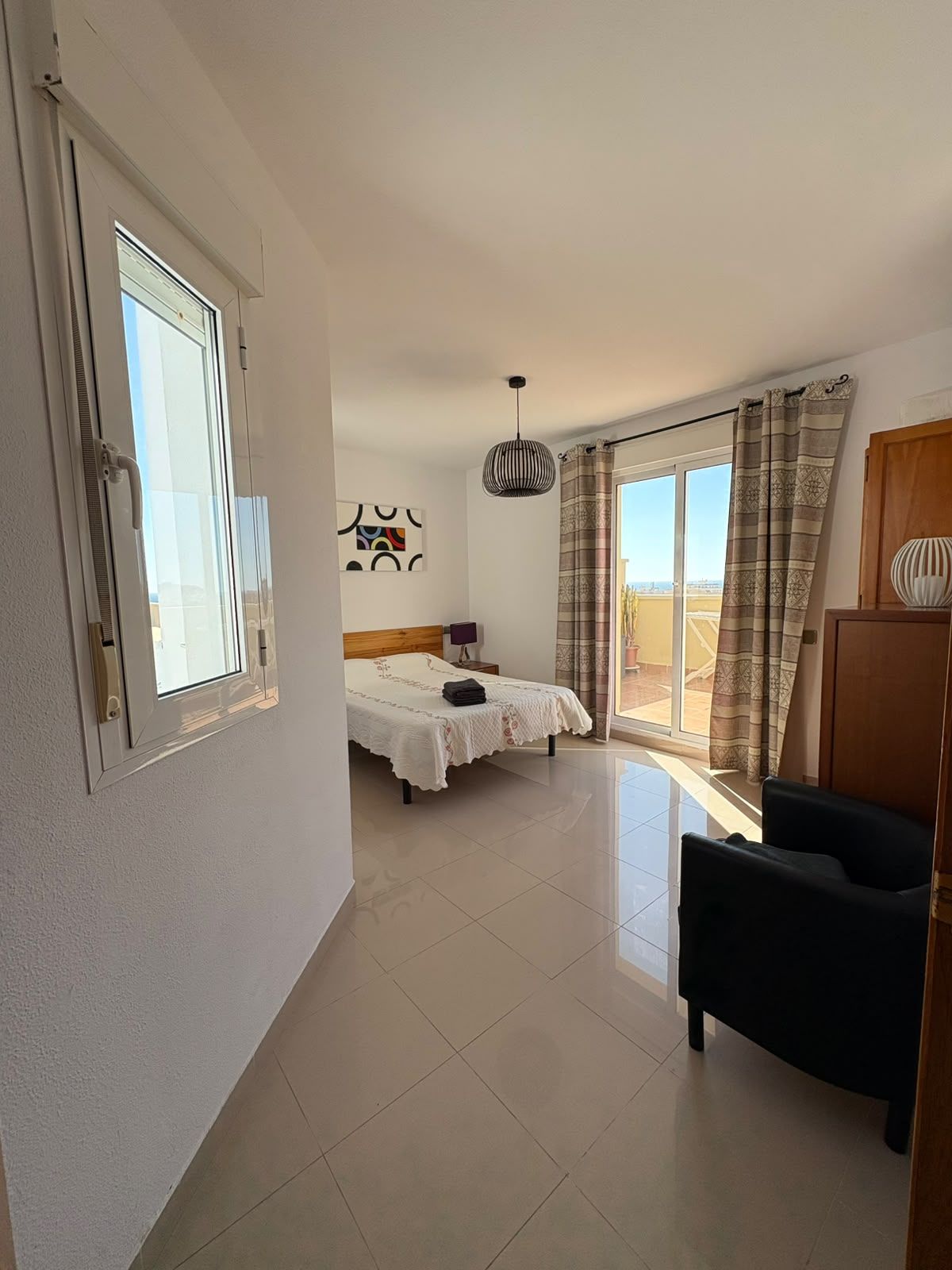 Ein Hotelzimmer mit Bett, Stuhl, Fenster und Blick nach draußen.